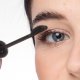 Eine Frau trägt Mascara mit einem Pinsel auf, verleiht ihren Wimpern Volumen und perfektioniert ihr Augen-Make-up.