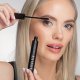 Eine Frau trägt vorsichtig Mascara auf ihre Wimpern auf und hält die Bürste nah an die Wimpern, um ein perfektes Finish zu erzielen.