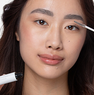 Eine Frau konzentriert sich darauf, Make-up mit einem Pinsel aufzutragen und so ihr künstlerisches Können und ihren persönlichen Pflegeprozess hervorzuheben.