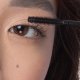 Eine Frau trägt Mascara mit einem Pinsel auf und konzentriert sich dabei auf ihre Wimpern, um einen definierten und eleganten Look zu erzielen.