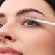 Eine Frau trägt mit einem Pinsel Mascara auf und betont so sorgfältig ihre Wimpern, um ein glänzendes und edles Aussehen zu erzielen.