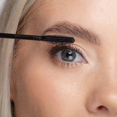 Model lächelt, während es Nanolash Mascara aufträgt